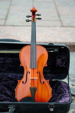 A violin is in a case in close-up. A street musician plays the violin.
