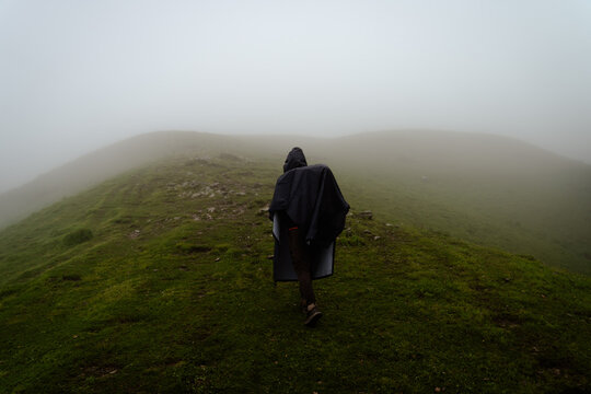 Lone hiker walking on a grassy mountain ridge in thick fog at Ali Bedni Bugyal, Chamoli, Uttarakhand, India