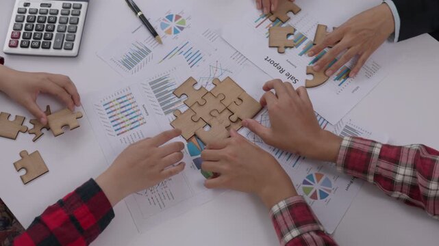 Concept of teamwork and partnership. Hands join puzzle pieces in the office. business people putting the jigsaws team together.