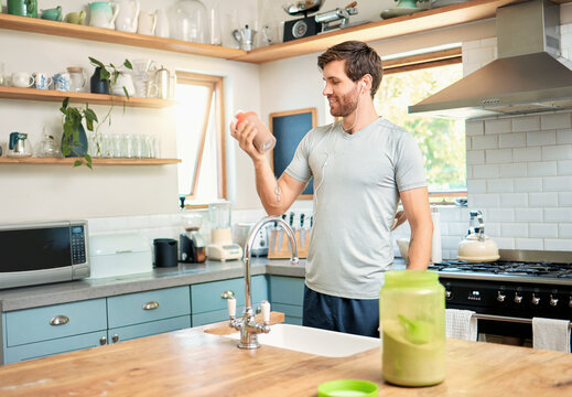 Smile, man and bottle with protein shake at house for fitness, nutrition and muscle growth. Happy, male person and earphones with beverage, supplement powder and post workout for bodybuilder wellness