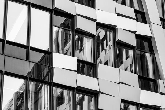 Black and white glass reflection sharpens the corporate building facade, making urban architecture, windows, and abstract geometry feel graphic