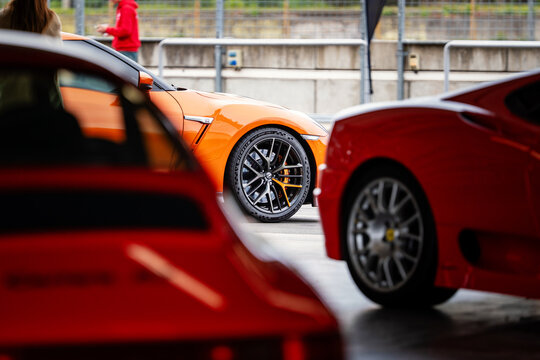 Brno, Czech Republic - May 14, 2026: Detail of the front wheel of an orange Nissan GT-R. View over two red sports cars.