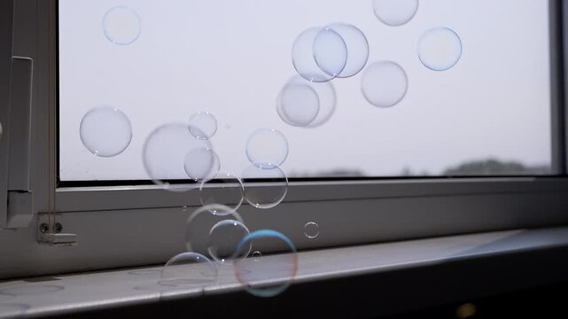 A multitude of shimmering, rainbow-colored soap bubbles slowly descend, accumulating and bursting on a sun-drenched windowsill. This scene evokes a sense of wonder and childlike delight.