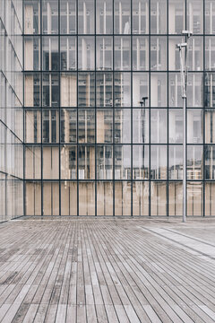 Modern glass facade rises above a quiet plaza, turning urban architecture and building lines into an exterior daylight grid of vertical panels