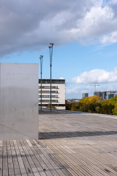Concrete terrace opens into an urban plaza, where architecture and building blocks meet exterior daylight sky along a clean horizon