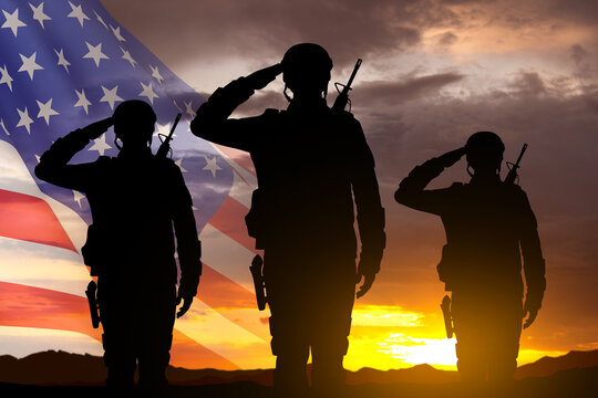 Silhouettes of a soldiers with USA flag against the sunset. Memorial Day, Veterans Day