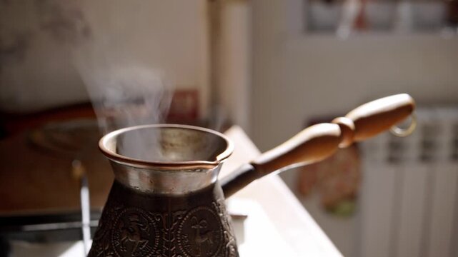 Thick steam rises slowly from a vintage copper cezve filled with hot coffee on a bright kitchen stove. Concept of traditional brewing methods, morning energy, and aromatic drinks.