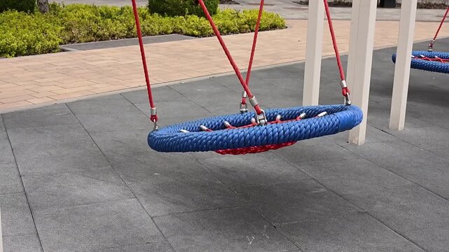 Nest swing moving gently at empty playground