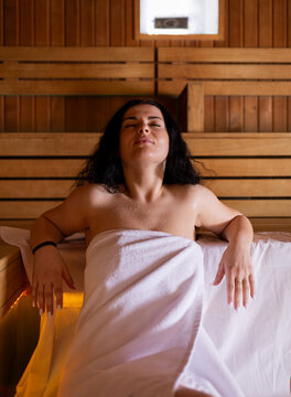 Portrait of a beautiful young woman with dark hair relaxing in a wooden sauna