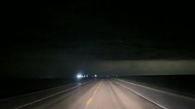 Driver point of view footage capturing nighttime driving conditions on dark rural roadway with illuminated dashboard and low light transportation scene