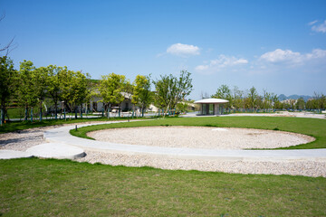 Fototapeta premium Green park landscape with circular path under blue sky and white clouds