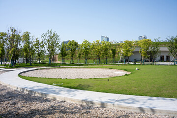 Fototapeta premium scenic view of a park with green lawn and curved pathway surrounded by trees