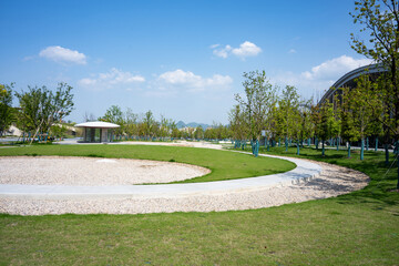 Fototapeta premium Park green space with winding paths under blue sky and white clouds