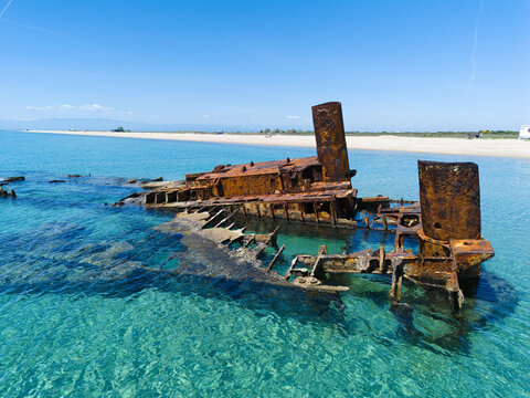 Aerial view of the rusty Shipwreck Epanomi submerged in turquoise shallow waters along a sandy beach under a clear blue sky Epanomi, Greece.