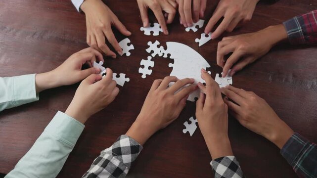 Concept of teamwork and partnership. Hands join puzzle pieces in the office. business people putting the jigsaws team together.