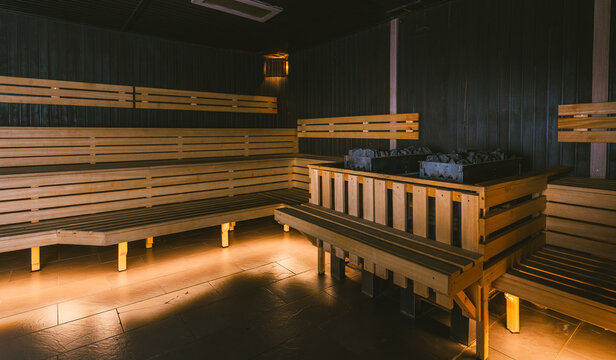 Interior of an empty large traditional dry sauna with wooden benches and a central heater