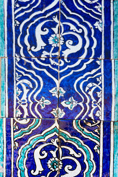 Ornate blue and white ceramic tilework with floral arabesque patterns from Islam Khoja Madrasah in Khiva. Detailed close-up of traditional Uzbek glazed tiles pattern, texture, background.