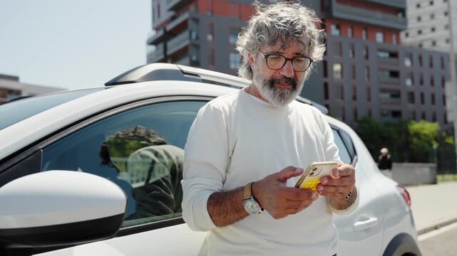 Senior man using mobile phone leaning on white car in urban city street for automobile insurance road assistance