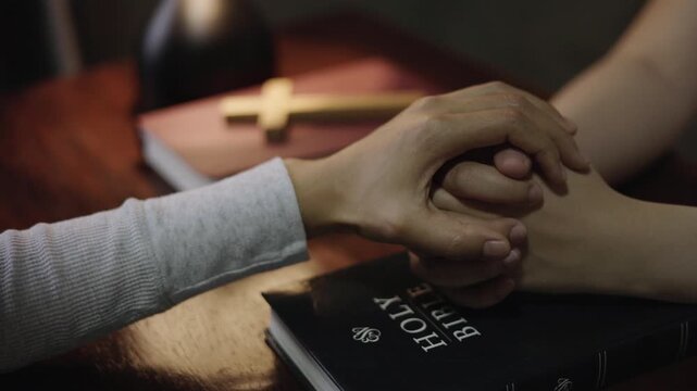 Christian group of people holding hands praying worships together to believe and Bible on wooden table for devotional for prayer meeting. Concept of faith for god.