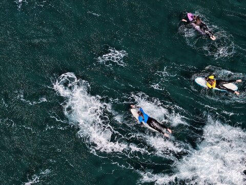 Aerial view of surfers paddling on their boards in the deep blue Atlantic waters off Praia do Areal de Santa Barbara in Ribeira Grande, Acores, Portugal.
