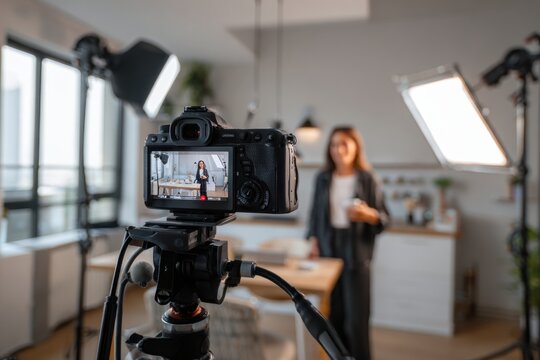 Professional content creator filming social media video with DSLR camera and studio lights in modern kitchen, showcasing influencer lifestyle in trendy apartment setting