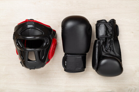 Boxing helmet and gloves on wooden background, top view.