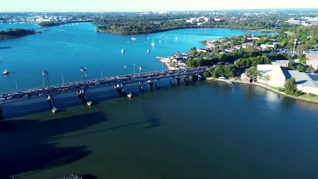 Drone aerial landscape of car vehicles driving across Ryde Bridge Road over Parramatta River with Brays Bay Reserve in the background at Meadowbank Sydney NSW Australia transport and infrastructure