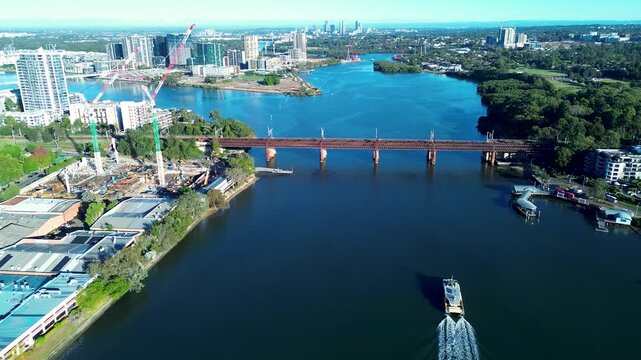 Drone aerial landscape of commuter ferry cruising along Parramatta River waterways surrounded by railway bridge and urban waterfront buildings in Meadowbank Sydney Australia transport infrastructure