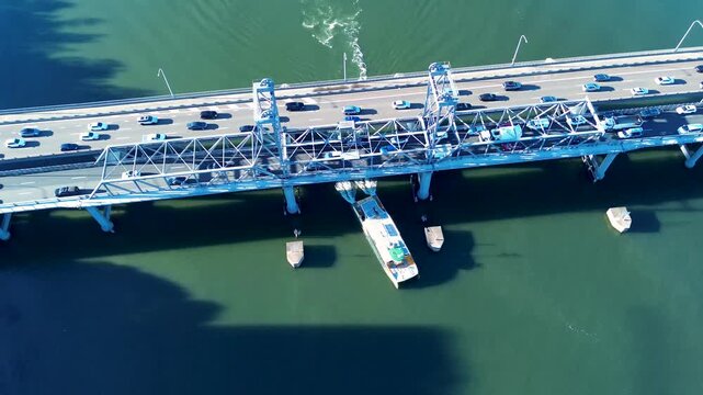 Drone aerial landscape of passenger marine ferry travelling underneath Ryde Bridge with car vehicle traffic moving along urban highway above near Parramatta River Rhodes Sydney NSW Australia transport