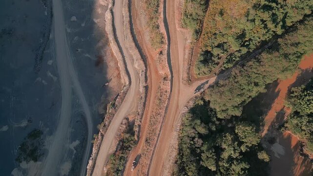 Top-down drone shot showing intersecting dirt haul roads carved through limestone terrain beside native vegetation at a cement quarry in Fercal, Brasilia.