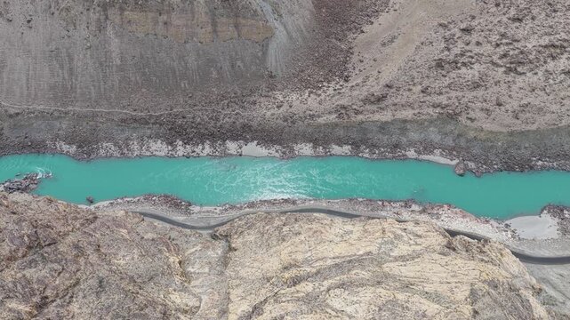 Cinematic nadir drone shot of scattered boulders and silty river channels in Skardu, Pakistan.