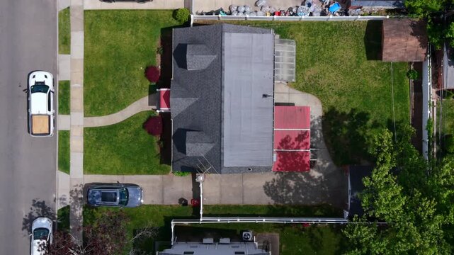 A top down view over houses in a residential neighborhood with beautifully landscape properties. Taken on a sunny day in spring. The camera tilted straight down dolly in over the residential area.
