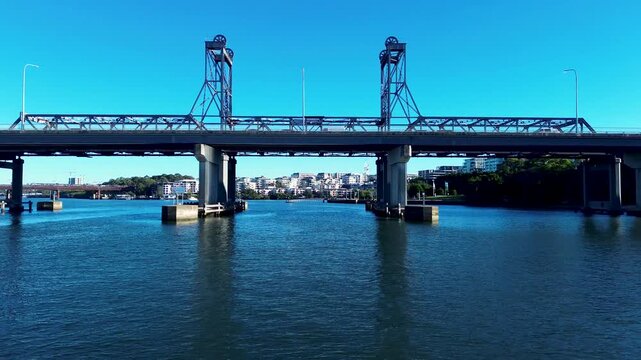 Drone aerial landscape of cars driving across Ryde Bridge showcasing the water surface underneath along the Parramatta River near the waterfront reserve in Meadowbank Sydney Australia marine travel