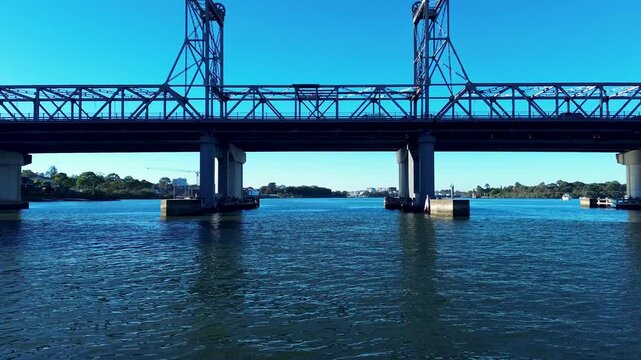 Drone aerial landscape of car vehicle traffic traveling across Ryde Bridge with surrounding waterfront harbour along the Parramatta River in Rhodes Sydney NSW Australia transport and marine tourism