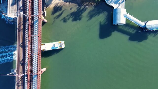 Drone aerial landscape of passenger ferry cruising underneath railway bridge tracks in harbour near waterfront wharf on Parramatta River Meadowbank Sydney city Australia travel transport and tourism