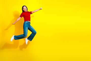 Obraz premium Young sporty woman jumps in red top and jeans against bright yellow background