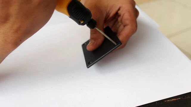 Close Up of Hand Using Portable Electric Drill to Make Screw Hole on Black Plastic Component