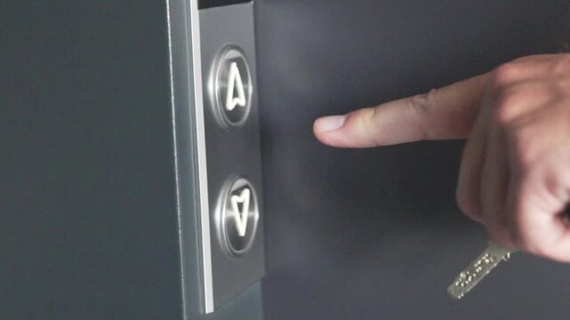 male hand pressing the elevator exit button up, the button lights up green