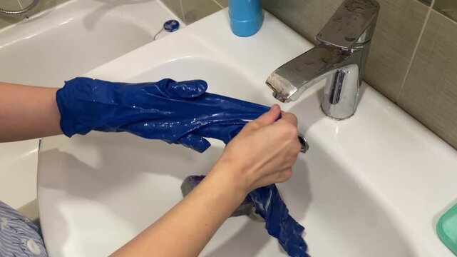 Cleaning process involves rinsing and wringing, Hands are carefully rinsed and wrung out after cleaning process, Thorough rinsing and wringing of gloves mark conclusion of cleaning procedures