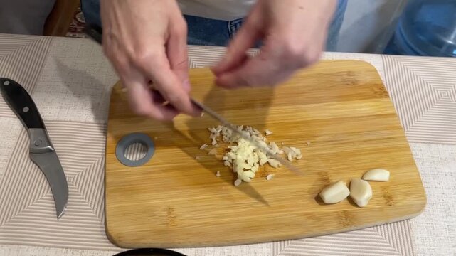 Cooking scene showing garlic being chopped and added, Scene depicts chef mincing garlic and incorporating it into soup, Scene illustrates chef chopping garlic and blending it into creamy soup