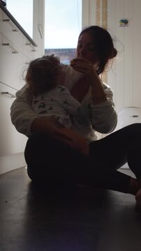 Mother trying to calm upset toddler offering fruit in kitchen dealing with tantrum concept of parenting stress patience and real everyday motherhood