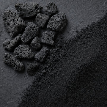 Diagonal split macro comparison of biochar granules versus activated carbon powder on black slate, sustainable carbon material types for soil amendment and water filtration, material science editorial