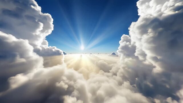 Majestic sun rays pierce through dramatic white clouds in a bright blue sky, creating a heavenly scene above the clouds.