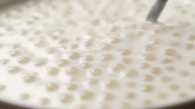 Delicious Creamy Tapioca Pearl Pudding Being Scooped by a Spoon in a Macro Close-up Shot, Showing Sweet Dessert Texture and Richness for Culinary Backgrounds.