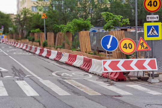 Roadwork zone redirects city traffic near crosswalk, with speed limit signs and barriers showing urban street safety measures.