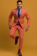 Fototapeta premium Smiling man jumping in orange suit on colored backdrop