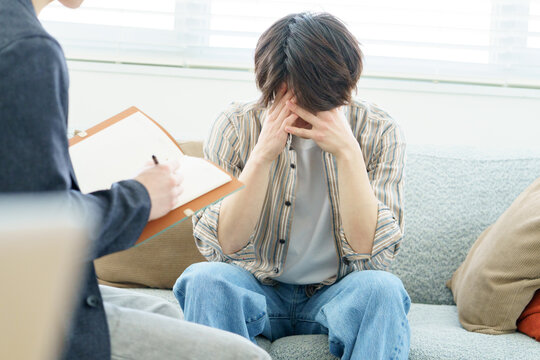 ソファに座ってカウンセリングを受ける若い日本人男性