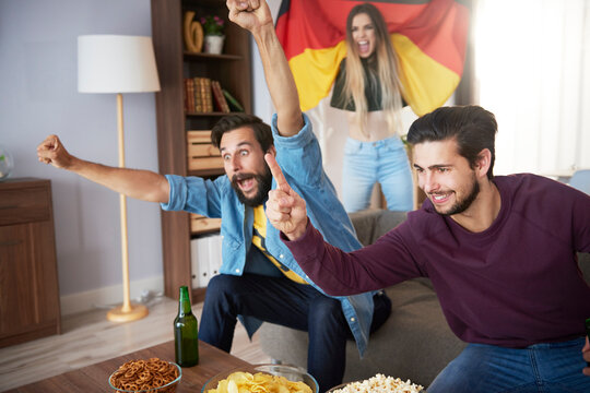 Excited German football fans watching Tv and cheering