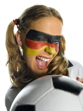 Woman with German flag painted on face holding ball, close-up