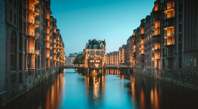 Hamburg Speicherstadt warehouse district with iconic Wasserschloss illuminated beautifully during blur hour at twilight, Germany